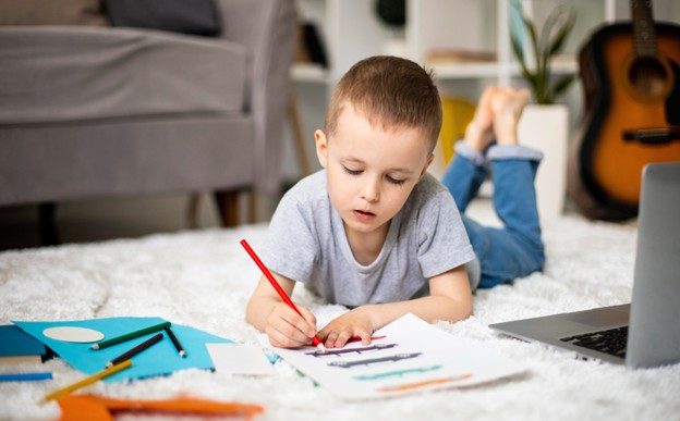 A child coloring on the floor of his home.